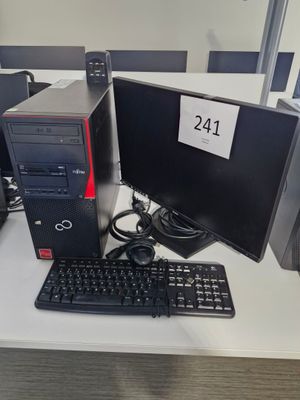 un ordinateur de bureau posé sur un bureau, à côté d'un clavier et d'un écran