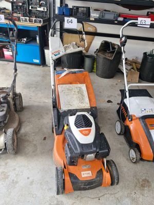 Plusieurs tondeuses à gazon sont alignées dans un garage