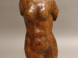 une photo représentant une sculpture en bois représentant un torse féminin posé sur un socle