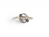 a close up of a diamond and sapphire ring on a white background