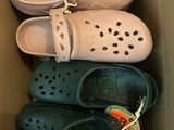 several pairs of crocs are in a cardboard box on the floor