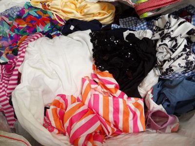 un tas de vêtements dans un sac en plastique posé par terre