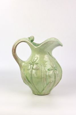 un vase vert muni d'une anse sur fond blanc