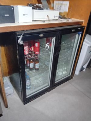 un réfrigérateur avec une porte vitrée dans lequel se trouvent des boissons