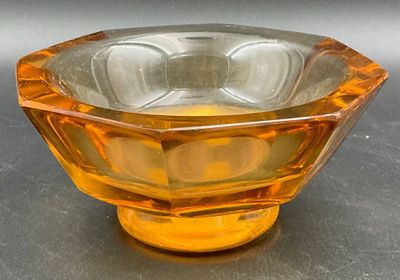 an orange glass bowl on a table with a gray background
