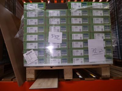 une palette remplie de cartons, elle-même posée sur une autre palette dans un entrepôt
