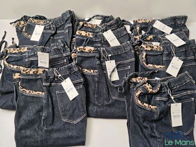 cinq paires de jeans, encore étiquetées, posées sur une table