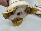 a white and gold statue of a dog with a hat on it ' s head