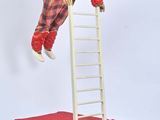une poupée qui se tient debout sur une échelle suspendue dans les airs