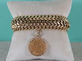 un bracelet en chaîne d'or orné d'une breloque en forme de pièce de monnaie
