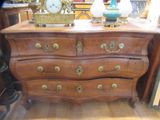 une commode sur laquelle est posée une horloge, dans une pièce