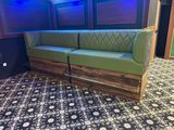 the couch is made out of wood and has a green seat