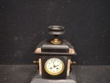 a small clock sitting on top of a black table