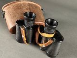 an old pair of binoculars with a leather case on a gray surface