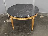 une petite table avec un plateau en marbre noir et des pieds dorés