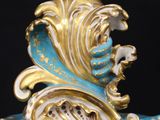 a blue and gold clock with a bird on top of it