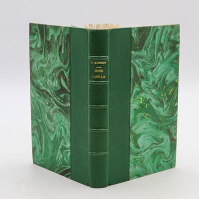 an old book with a green cover sitting on top of a white table