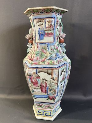 un grand vase avec un tableau posé sur une table