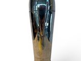 a silver vase that is sitting on a white surface