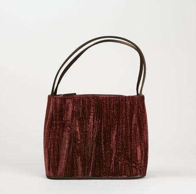 un sac à main en velours rouge avec une anse en cuir