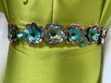 the belt is made of metal and has flowers on it