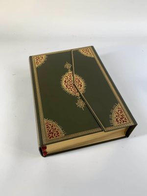 un vieux livre à la couverture verte, rehaussée de dorures sur fond blanc