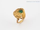 an image of a gold ring with a green stone surrounded by leaves