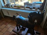 un cheval à bascule devant une fenêtre, dans une pièce