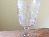 a glass on a wooden table with a white wall in the background