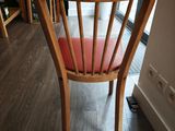 a wooden chair with a red seat in the corner of a room