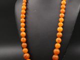un collier de perles orange sur un mannequin noir