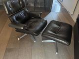 un fauteuil et un repose-pieds en cuir noir dans un salon