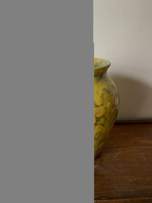 un vase jaune posé sur une table en bois près d'un mur blanc