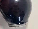 a hand holding a small black vase on a table
