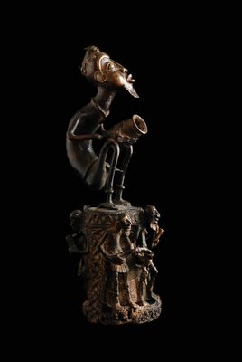 une statue en bronze représentant un homme jouant de la trompette au sommet d'une souche d'arbre