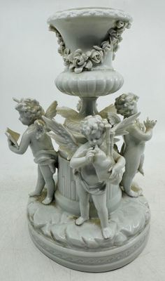 un vase blanc orné d'anges, posé sur un socle