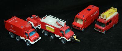 quatre camions de pompiers miniatures alignés sur une surface noire