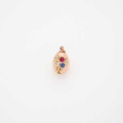 une image représentant un pendentif en or orné d'une pierre rouge, bleue et verte
