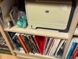 une imprimante posée sur une bibliothèque, devant un téléviseur