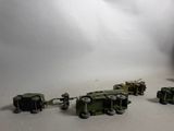 several toy army vehicles are lined up in a row on a white surface
