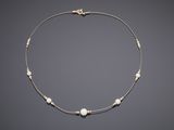 a gold and pearl necklace on a gray background