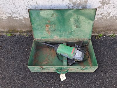 a green box with a drill in it sitting on the ground