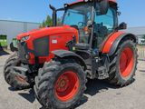 un tracteur rouge garé sur un parking à côté d'un bâtiment
