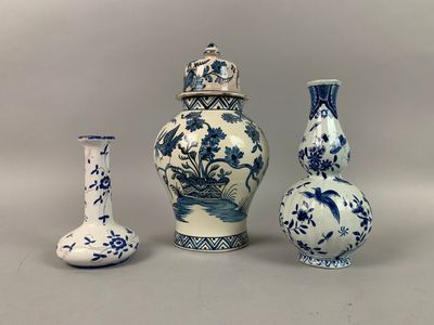 trois vases bleus et blancs sont alignés sur un fond gris