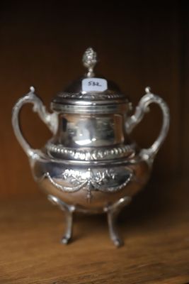 une théière en argent posée sur une table en bois, sur laquelle est accrochée une étiquette