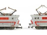 two model trains sitting side by side on a white surface