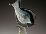 a glass sculpture of a bird sitting on a stand