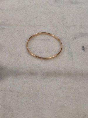 un gros plan d'une bague en or posée sur une surface en marbre