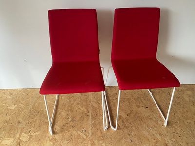 pair of red chairs with metal legs in a white room