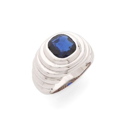un gros plan d'une bague sertie d'une pierre bleue sur fond blanc